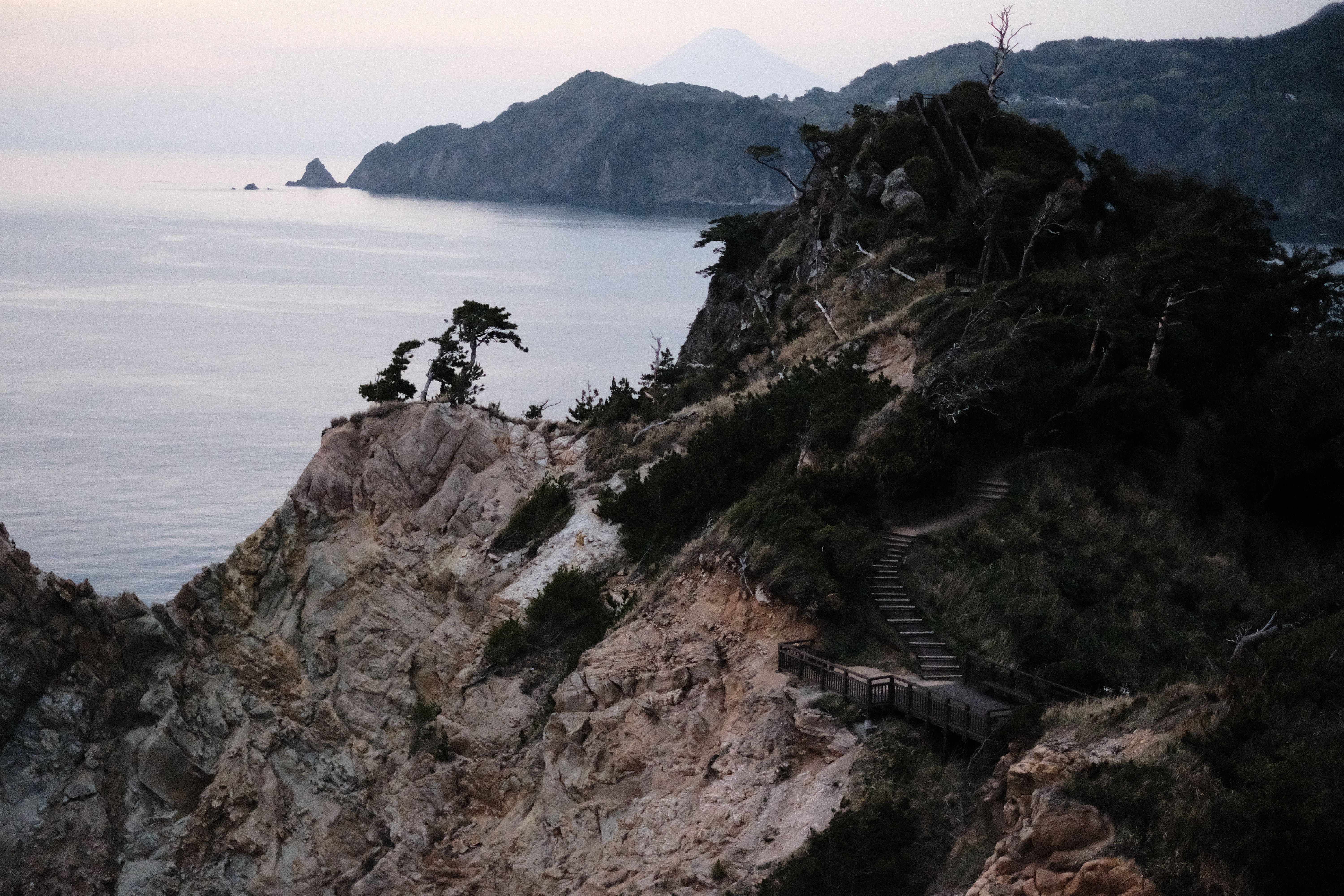 A coastal mountain path with a distant peak